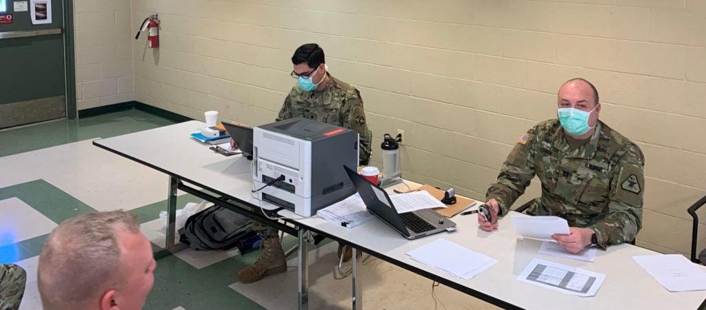 Army officers wearing facemasks at army reserve hospital, doing paperwork