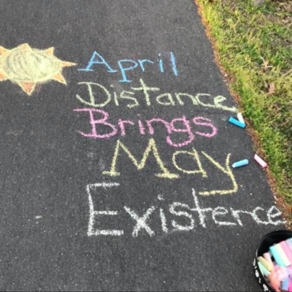 Text drawn on a street with chalk, with the words: "April distance brings May existence"