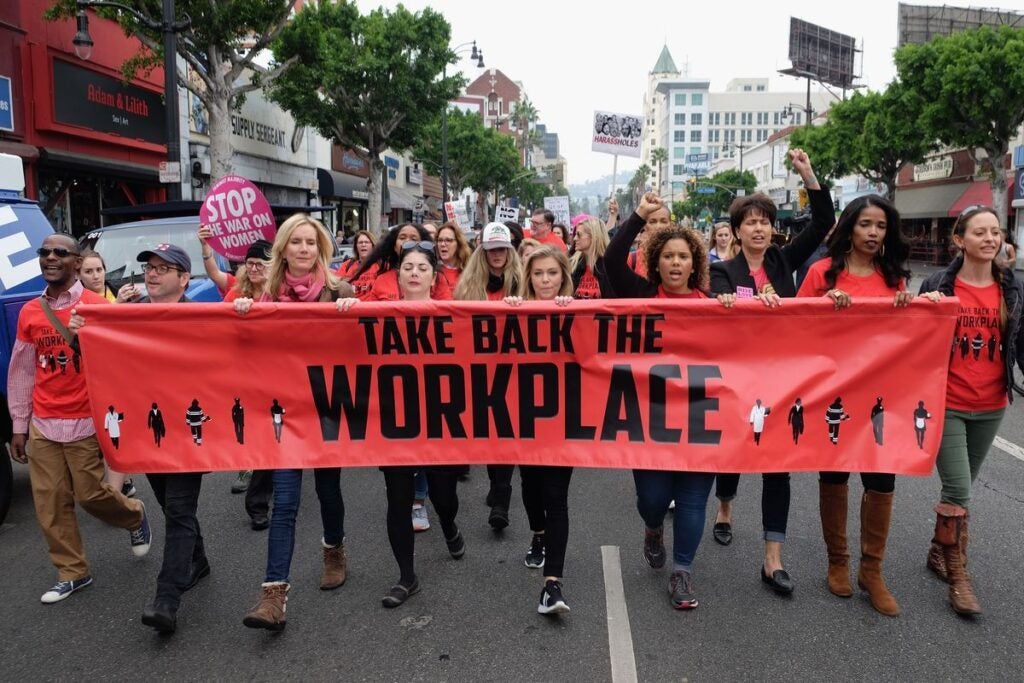 Women marching in Los Ángeles, holding signs demanding to "Stop the War on Women" and "Take Back the Workplace"