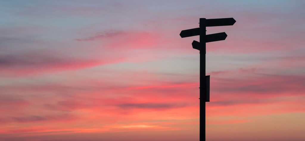 Futurity landscape displaying a sign pointing at a crossroads at dawn