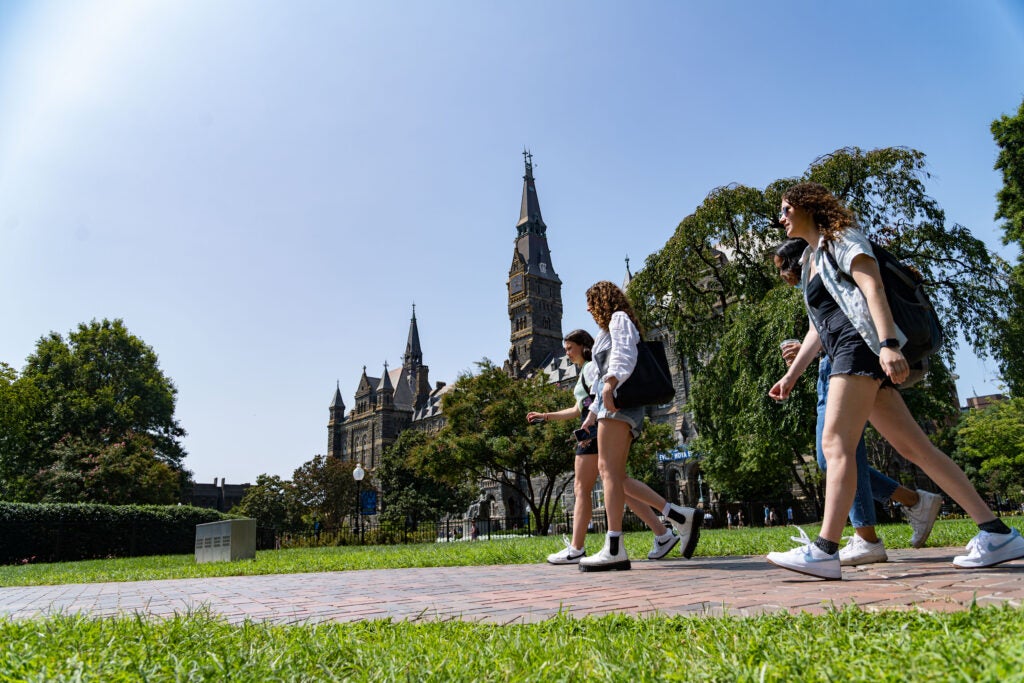 Georgetown Students walking across the main campus with Healy Hall in the background.