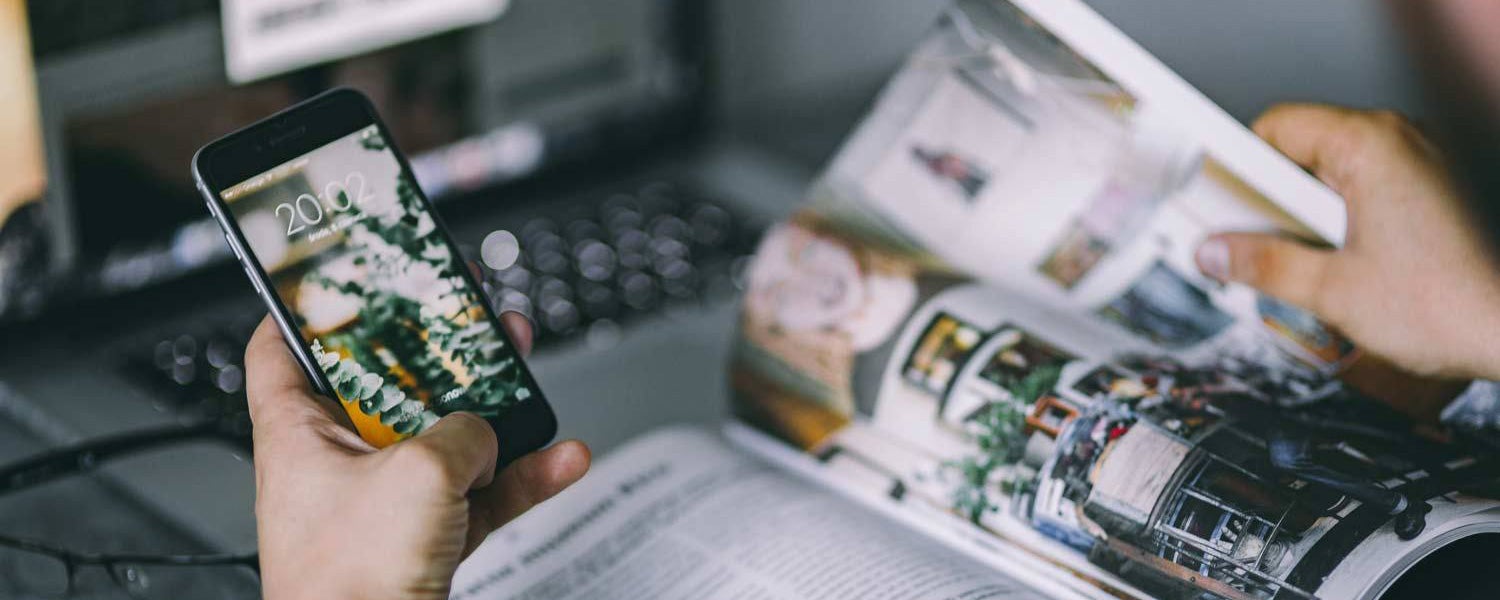 Person holding cellphone next to an open laptop and open book, with an illustration of useful technology