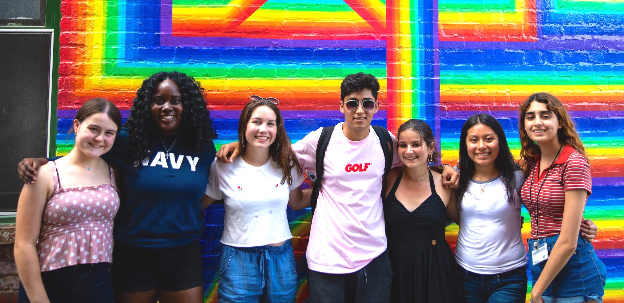 seven students in front of a colorful mural