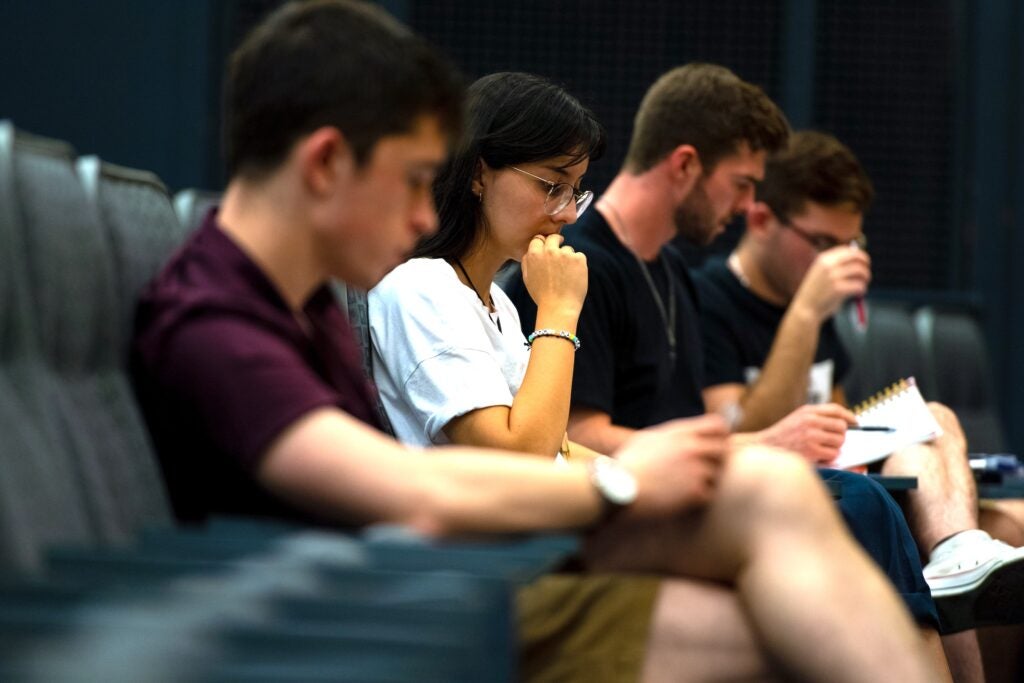 Four students sitting together in an auditorium hall listening to a lecture.