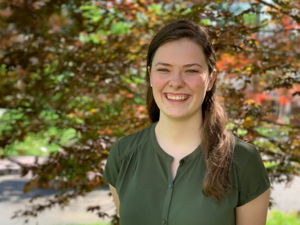 Christina Ribbens waring a green shirt with trees in the background.