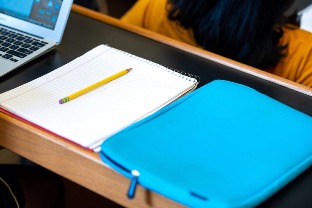 Laptop, notebook and laptop case on a classroom desk